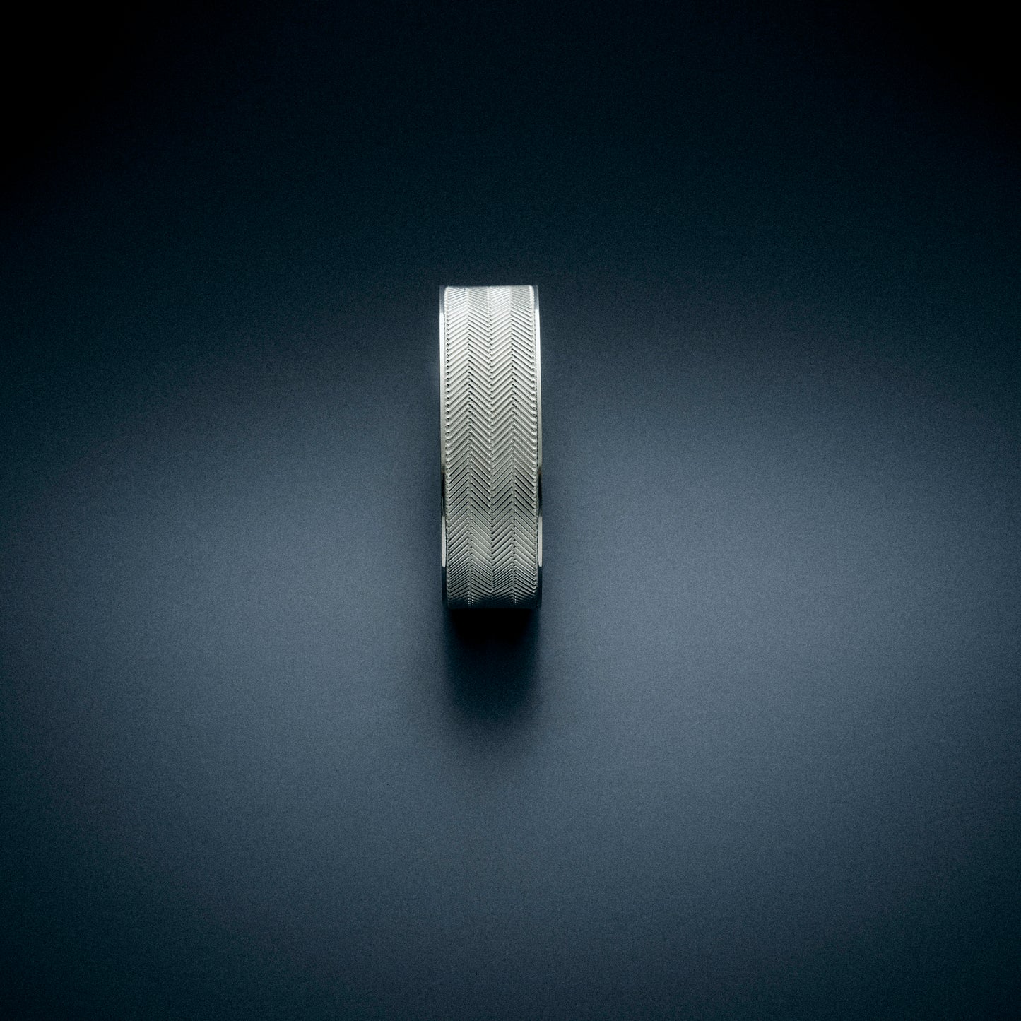 A top view of a silver bracelet with a herringbone cnc engravement